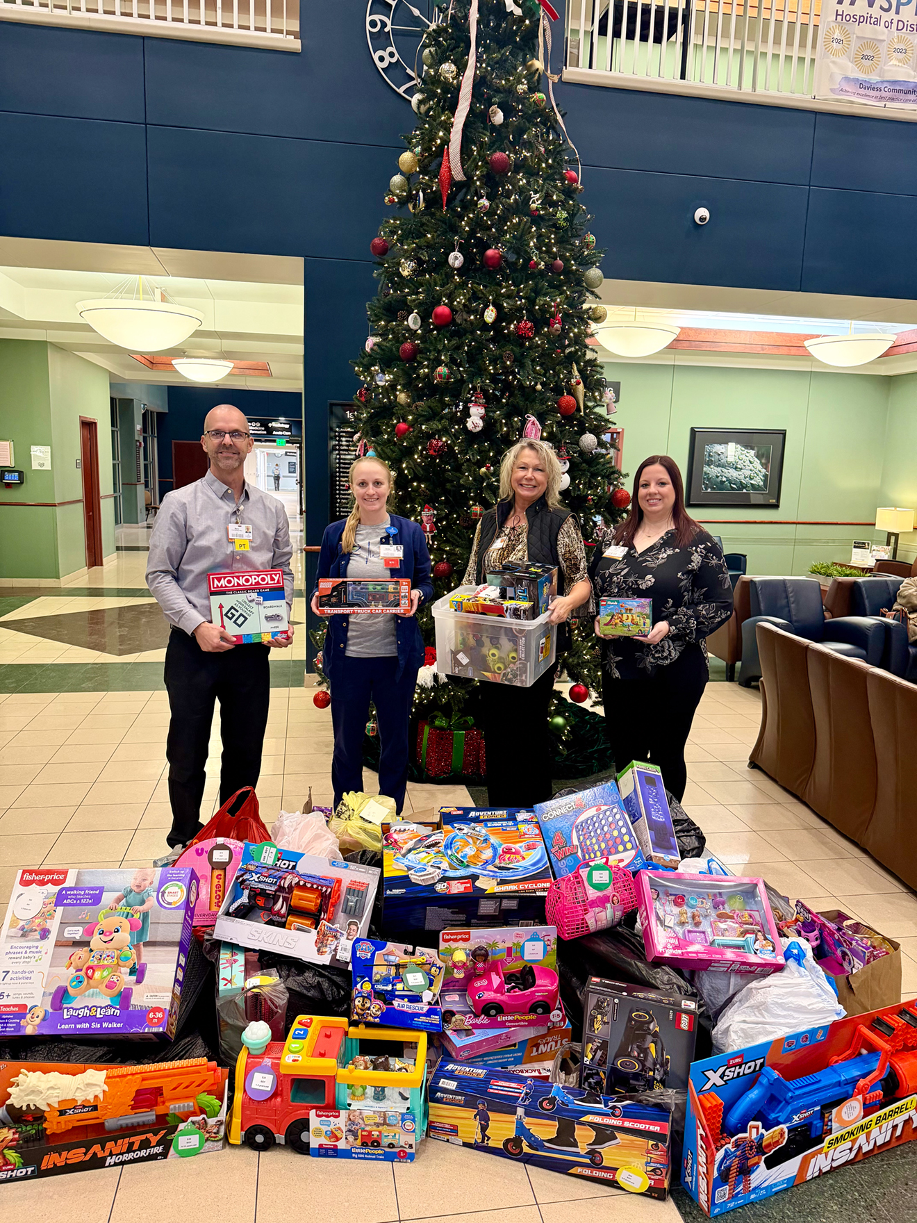 From left: Dave Graber, Chief Operating Officer; Jenna Bedwell, MSN, RN, NE-BC, Chief Nursing Officer; Angie Steiner, Director of the DCH Foundation; and Tia Collison, Executive Project and Medical Staff Coordinator, stand with a portion of the toys and gifts collected by Daviess Community Hospital staff for Jubilee Christmas. The holiday assistance program, coordinated by CONNECTIONS, supports more than 500 children across Daviess County each year.